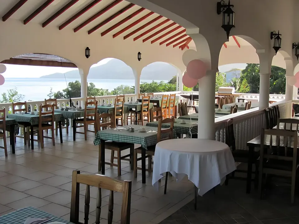 Restaurant tables set under the arches of the veranda, with the ocean beyond